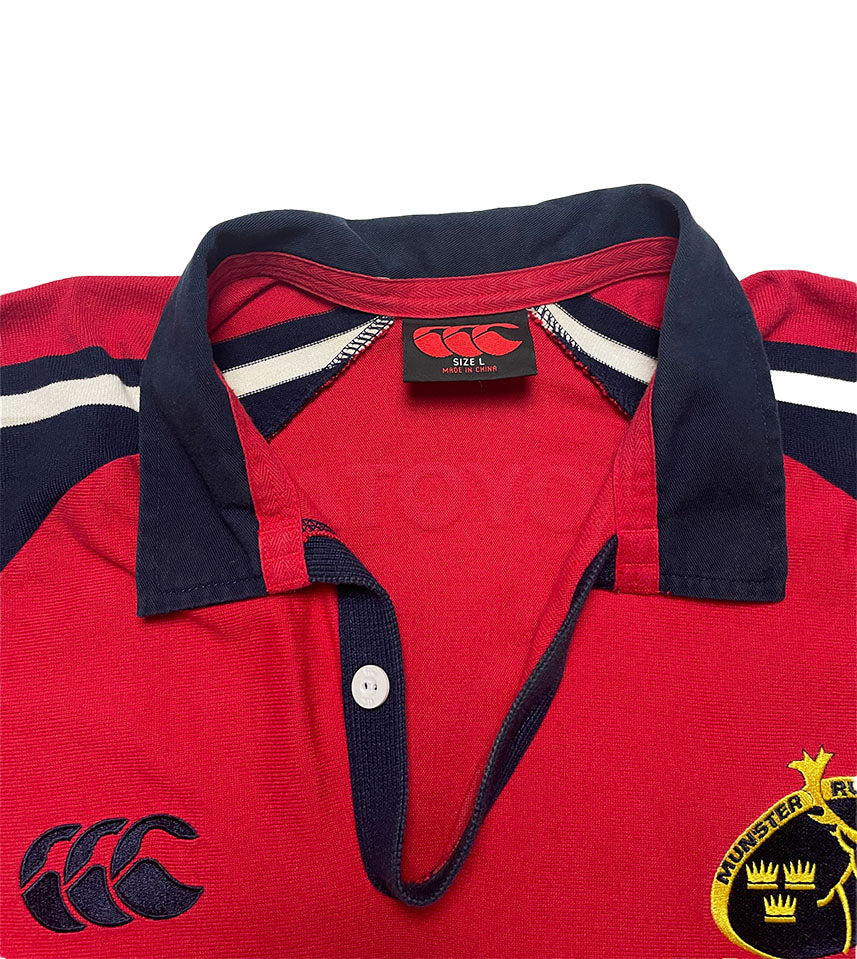 Red rugby jersey with navy collar and white stripes, featuring a brand tag and logo.