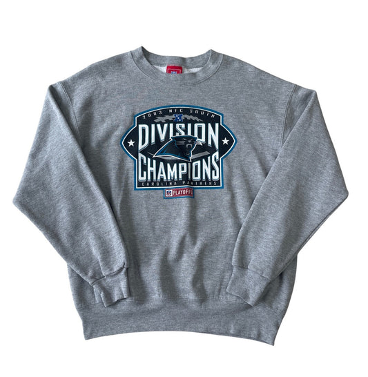 A heather gray crewneck sweatshirt featuring a large graphic on the front that reads '2023 NFL Football Division Champions' with the Carolina Panthers logo and a red 'Panthers' brand tag below it, displayed on a clean white background.