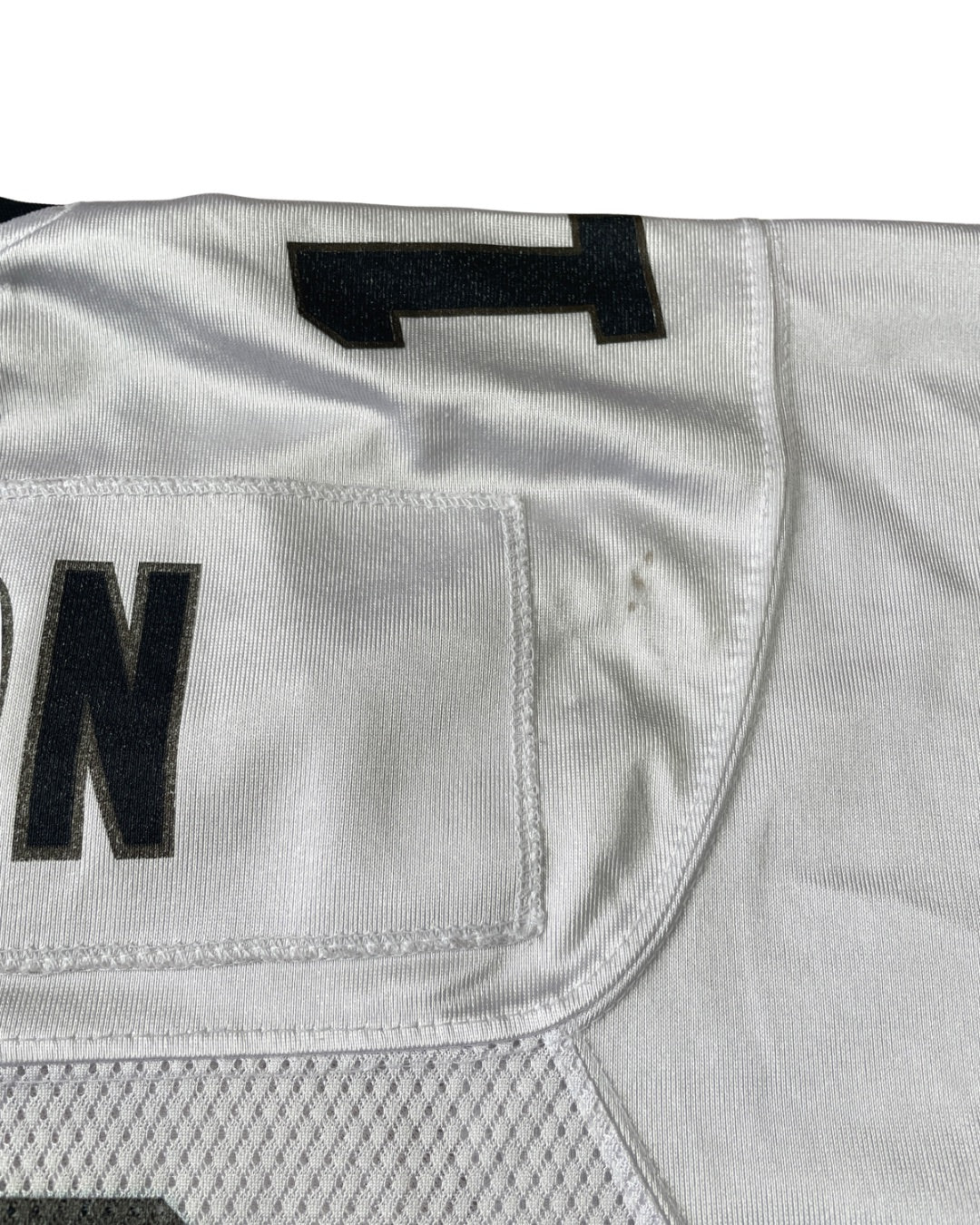 Close-up of a white athletic jersey showing part of the number 1 and the letters 'N' and 'D' in black, with a mesh panel at the bottom.