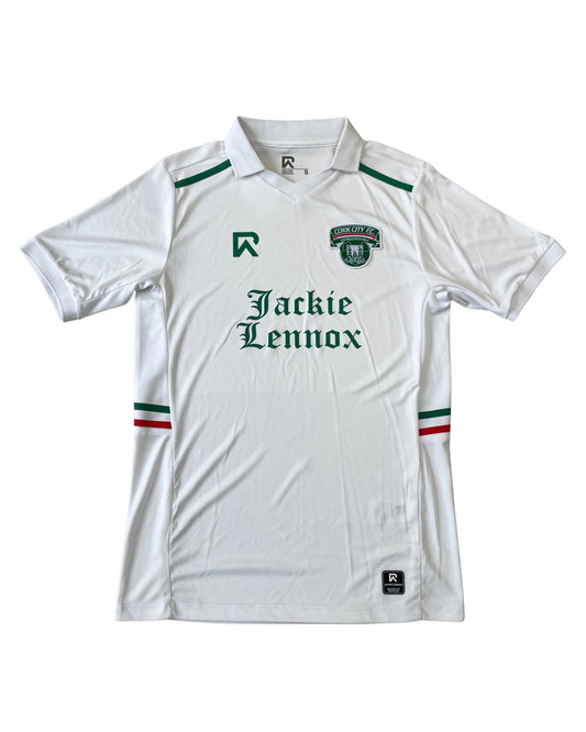 A white short-sleeve soccer jersey with green and red accents, featuring the text 'Jackie Lennox' across the chest and a club crest on the left chest. The jersey is displayed flat against a white background.